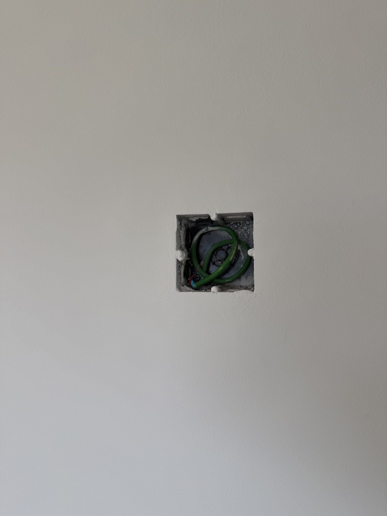 Open wall box with cable and unfinished edge.