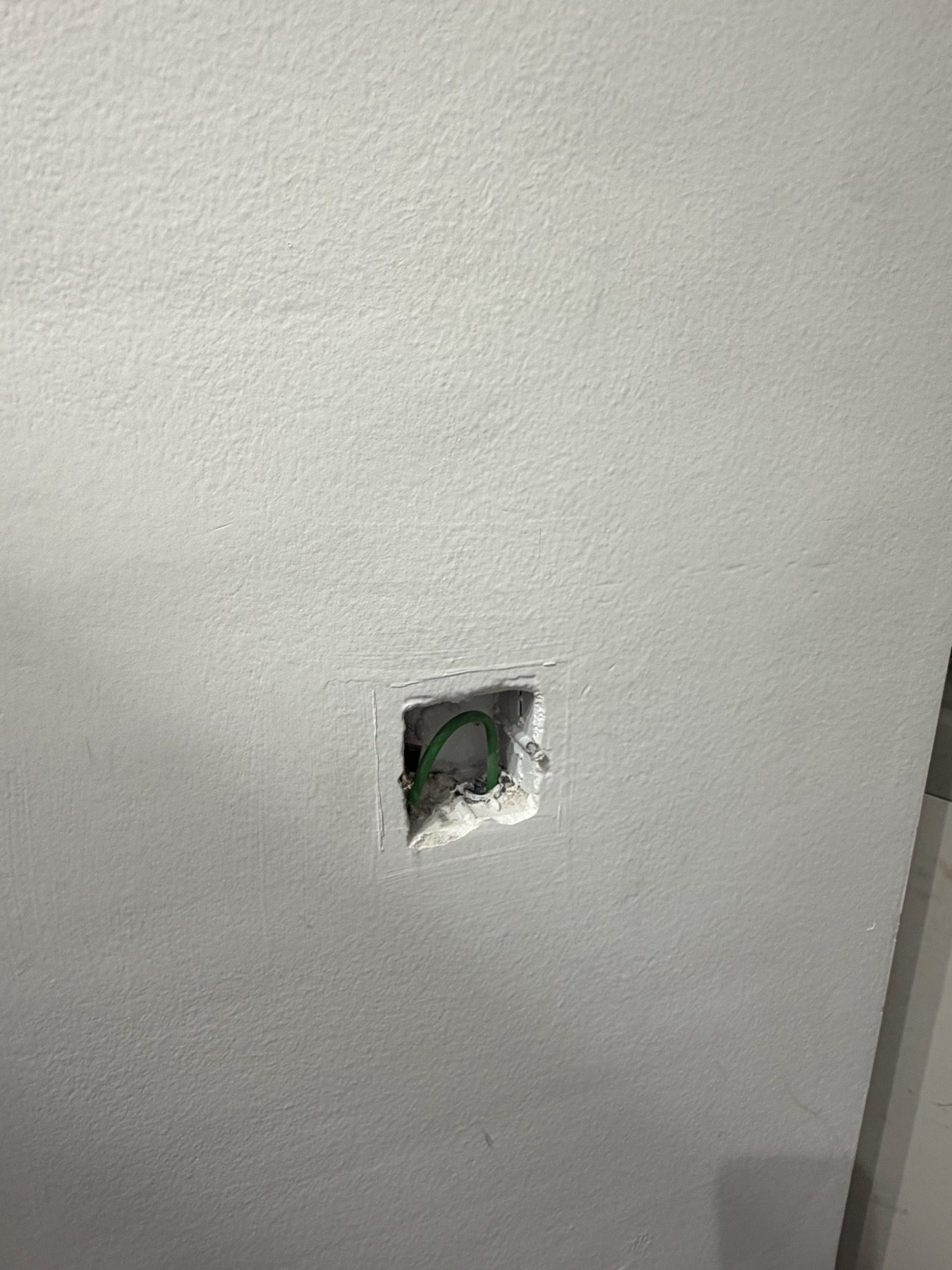 Open wall box with cable and damaged surrounding finish.