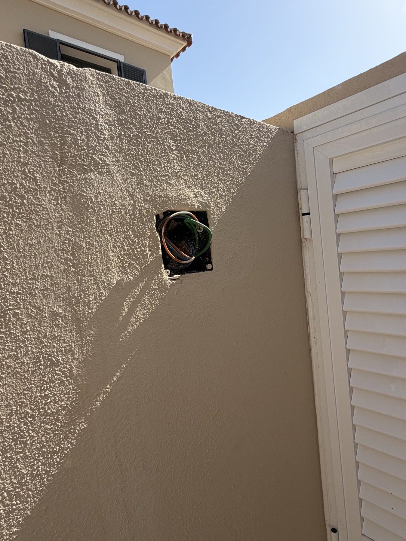 Uncovered exterior wall box with cables exposed.